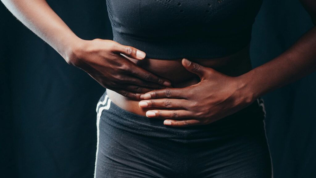 Femme qui pose la main sur son bas-ventre lors d'un examen gynécologique