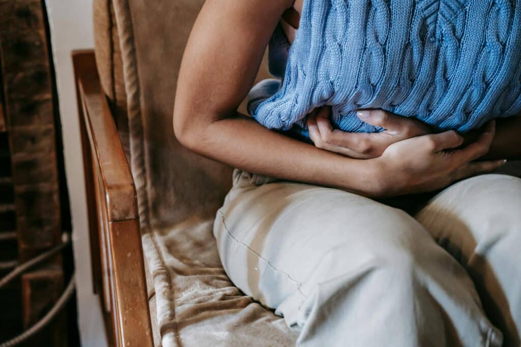 Femme allongée tenant son ventre en signe de douleur intense lors de règles hémorragiques
