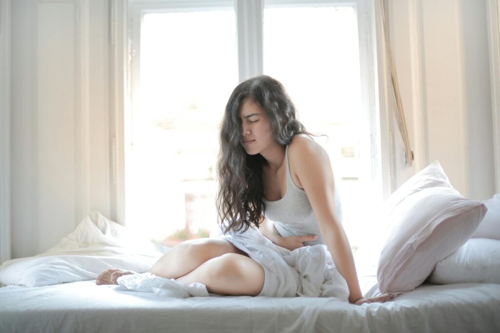 Femme allongée tenant son ventre, douleur pelvienne sans menstruation visible