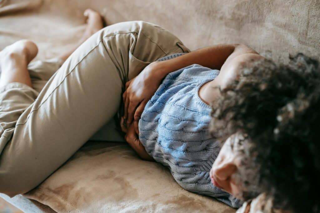 Femme allongée tenant son ventre douloureux, lumière douce, contexte endométriose