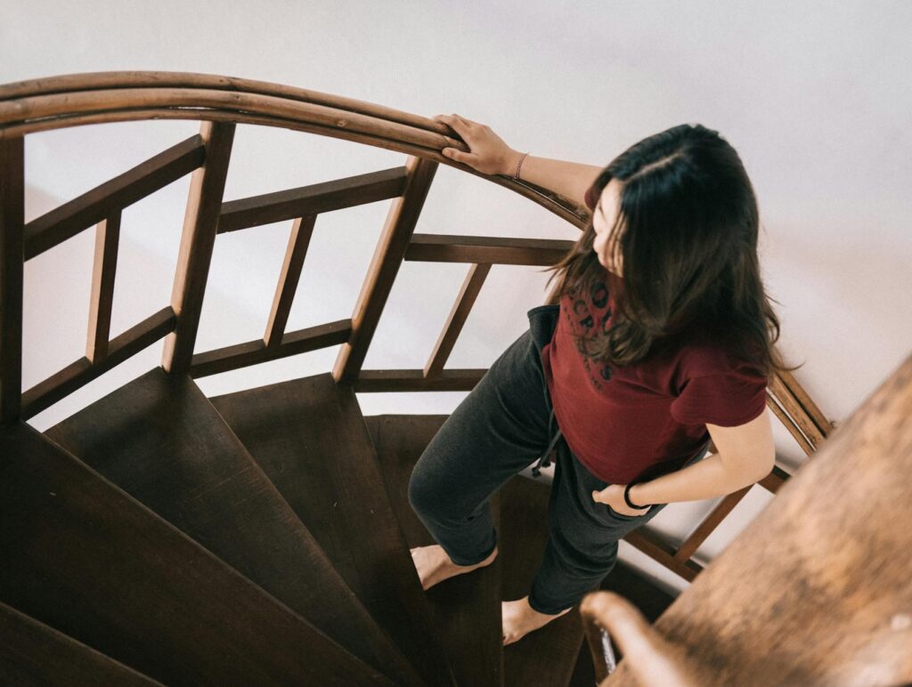 femme tenant une rampe d'escalier après une opération gynécologique à domicile