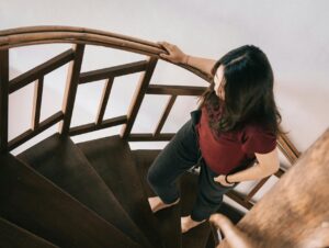 femme tenant une rampe d'escalier après une opération gynécologique à domicile