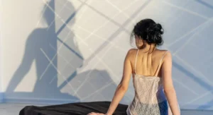 Femme silencieuse, lumière tamisée, allongée sur un lit, regard introspectif