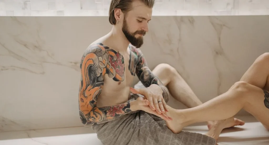 Mains féminines massant délicatement un dos nu à la lumière tamisée