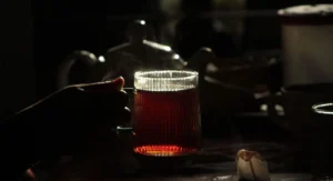 Un homme souriant boit une infusion maison dans sa cuisine le soir
