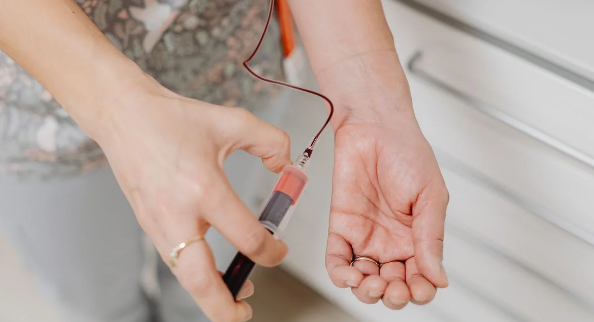 A close-up view of a blood draw procedure with syringe and vial, focusing on healthcare treatment.