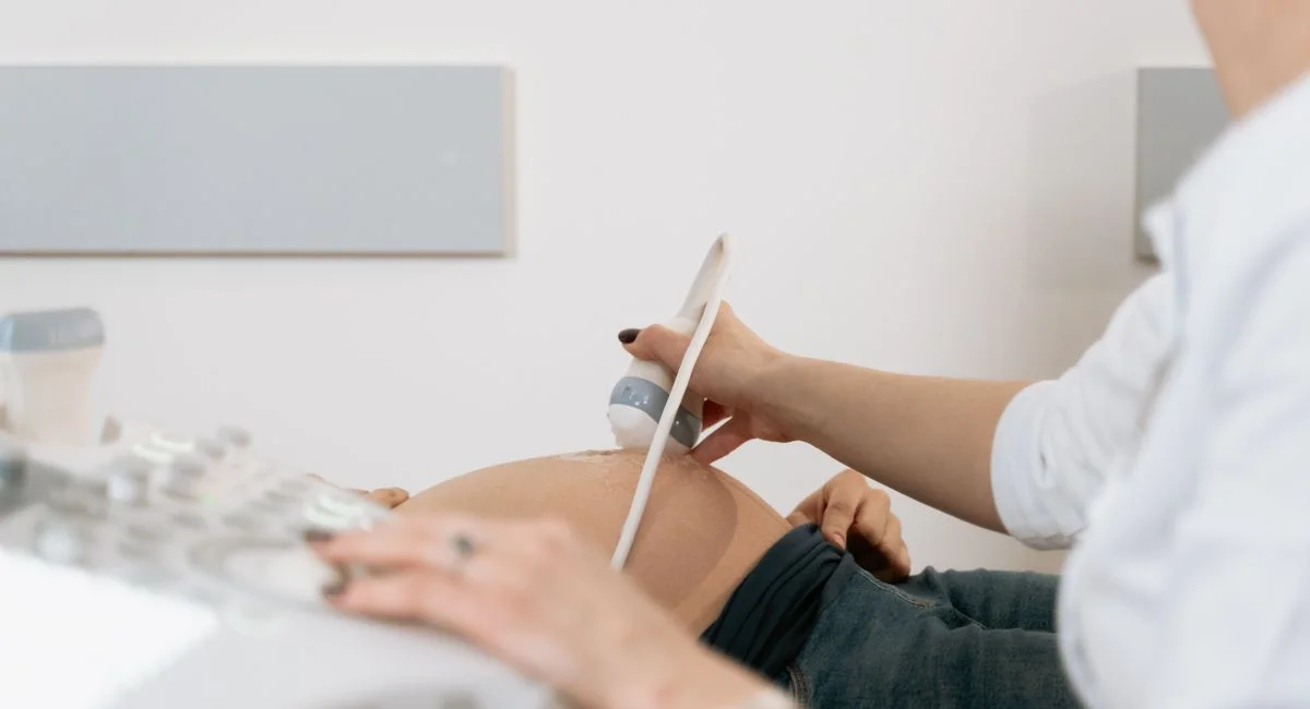 A healthcare professional performs an ultrasound on a pregnant woman in a clinic.