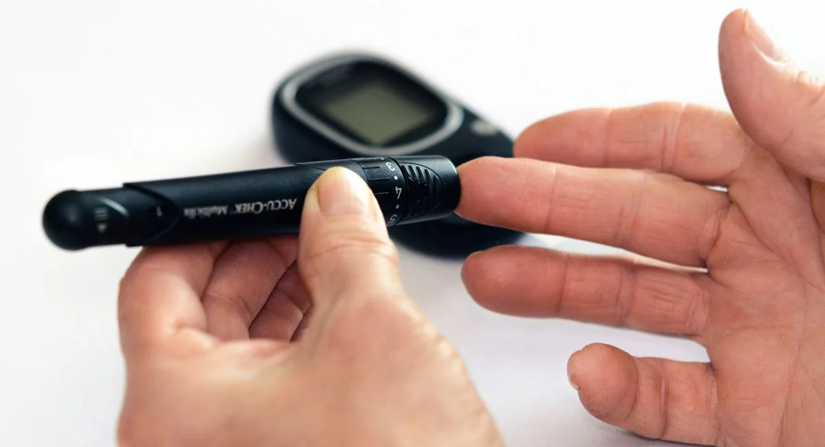 Close-up image of a person using a glucometer for diabetes management indoors.