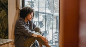 Femme assise, regardant son ventre, main posée sur la taille