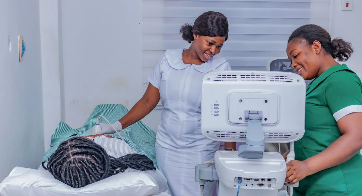 Smiling healthcare professionals performing an ultrasound examination in a clinical setting.